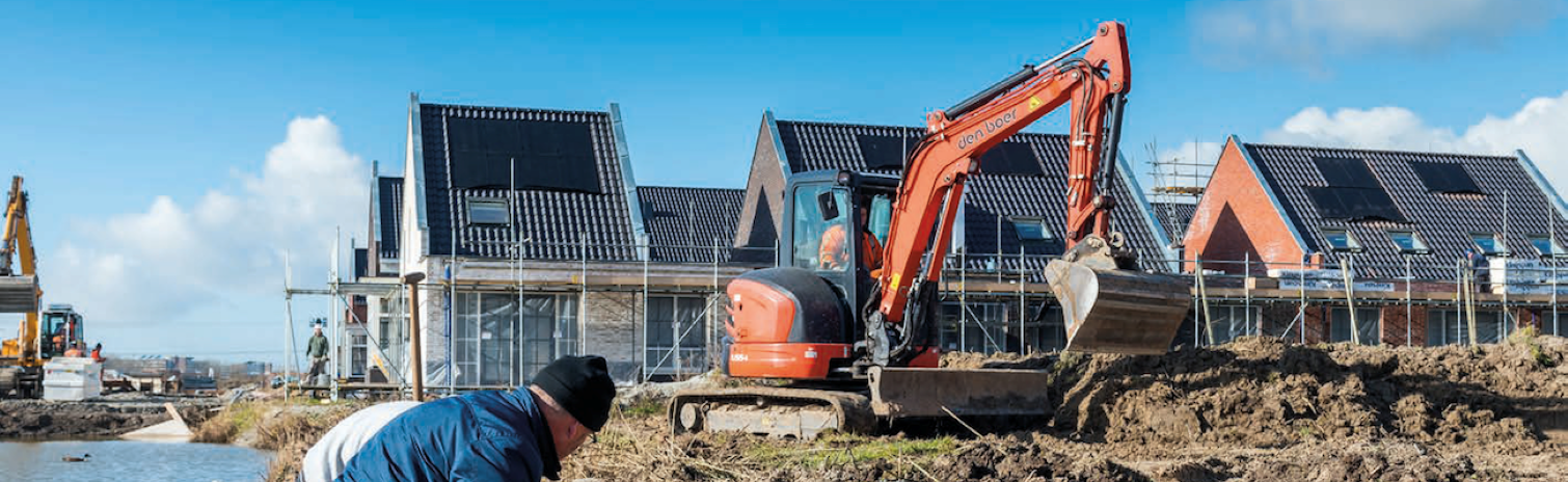 Op de voorgrond werkt een man. Op de achtergrond staan huizen in aanbouw.